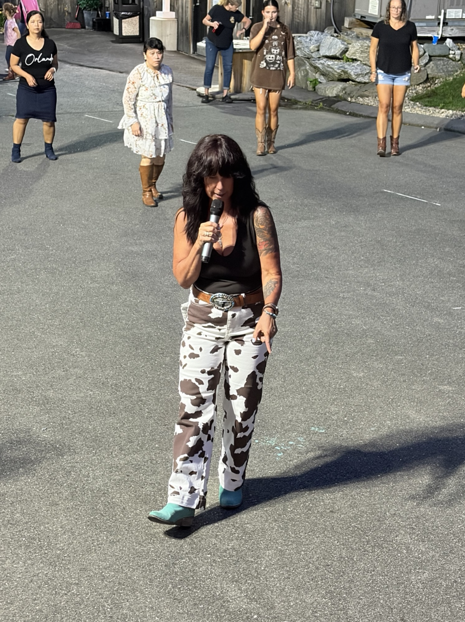 Nicole teaching an outdoor line dance class with a microphone