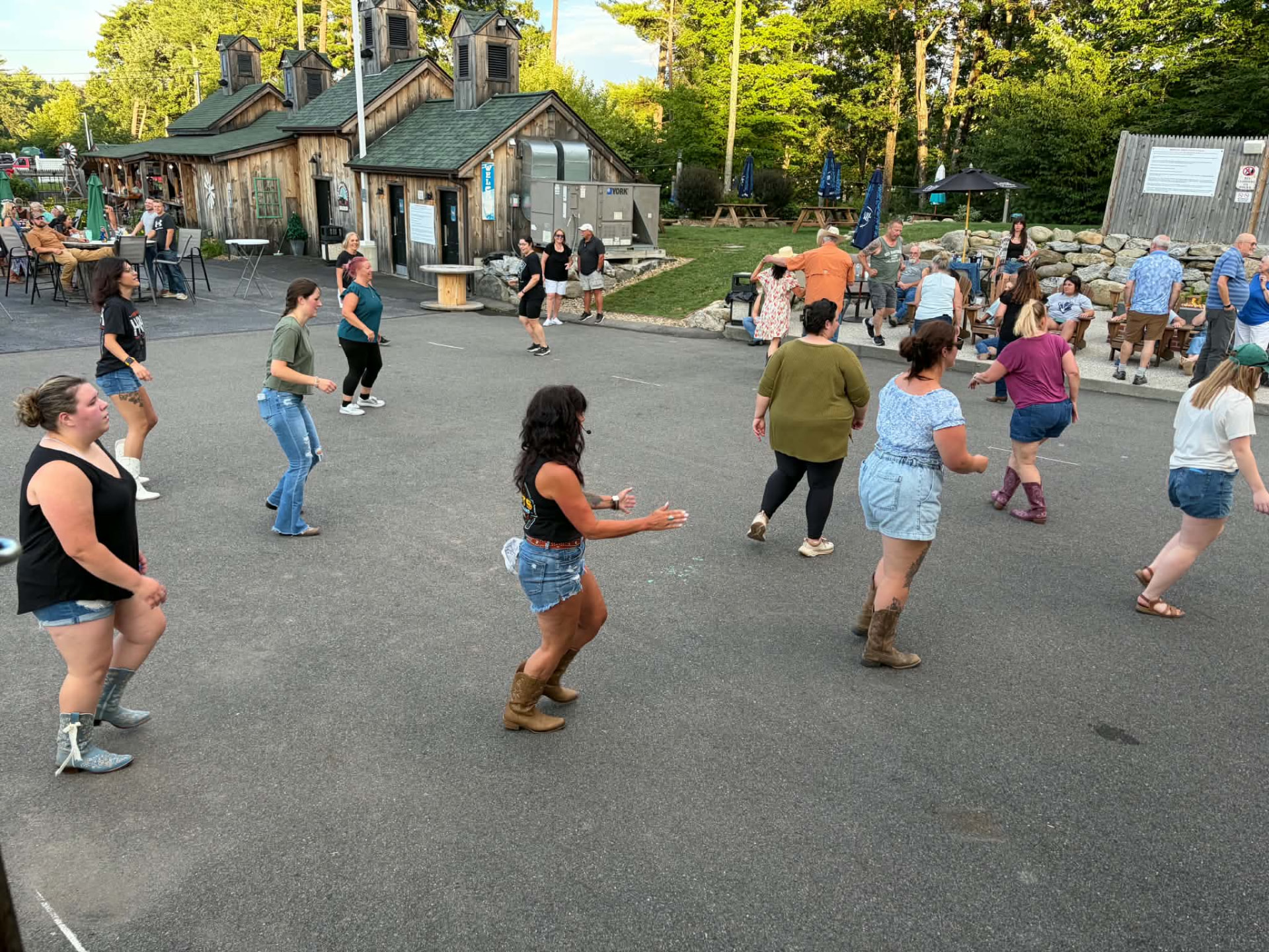 Dancers line dancing outdoors at a Boots on the Ground night at The Barnyard