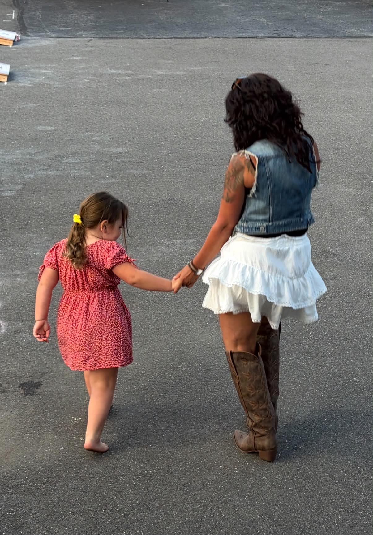 Nicole walking hand in hand with a young dancer at a Boots on the Ground night